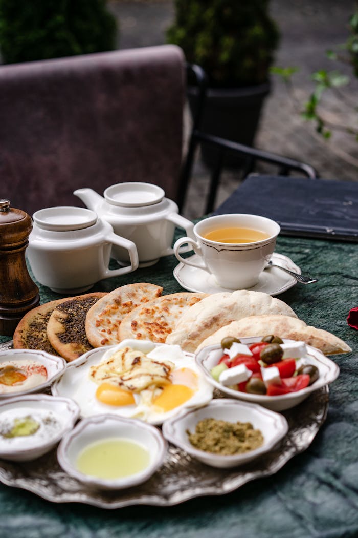 services-02 A sumptuous Middle Eastern breakfast spread on an outdoor table with various dishes and a tea set.