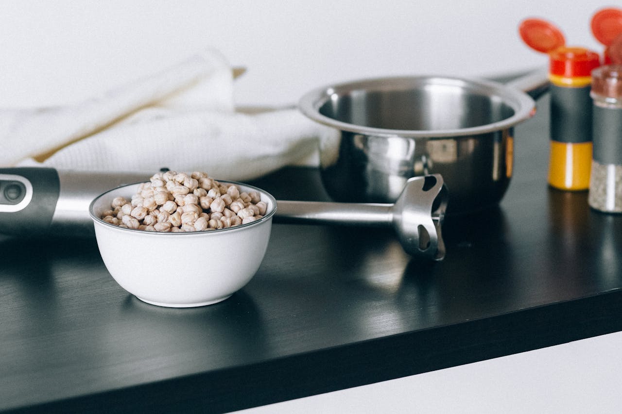 services-04 Bowl of chickpeas with cooking tools and spices on kitchen counter.